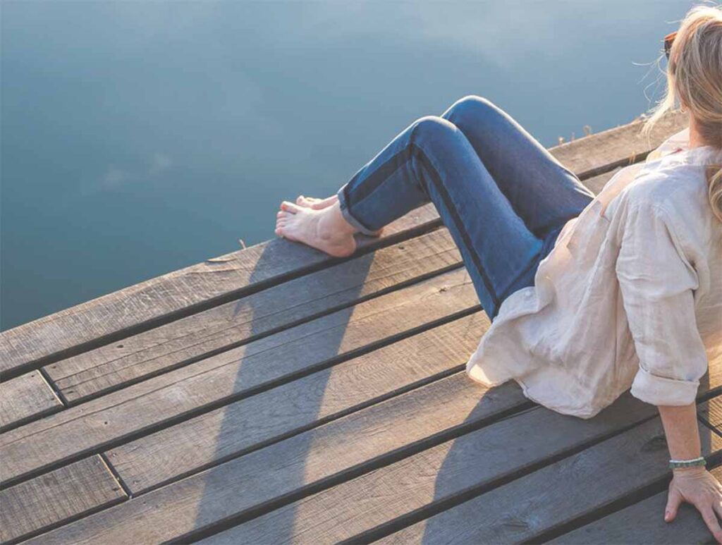 Woman sitting on dock by water