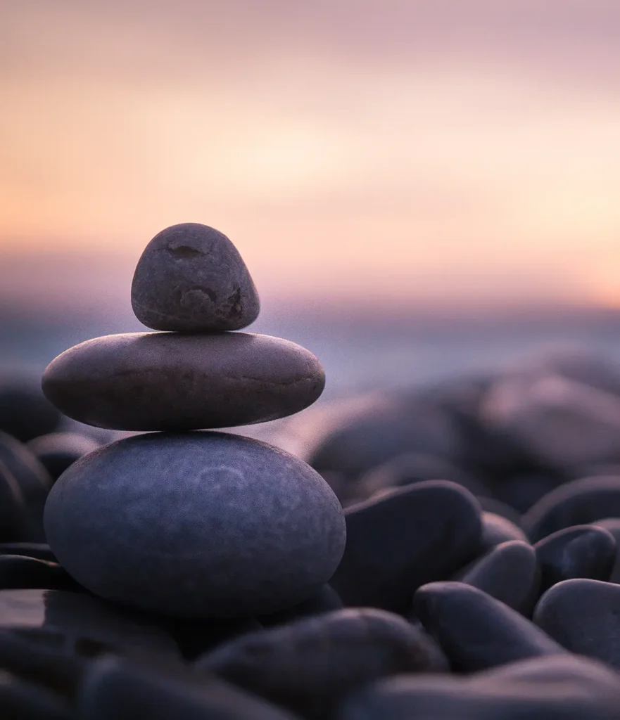 Three round stones stacked against purple sky background